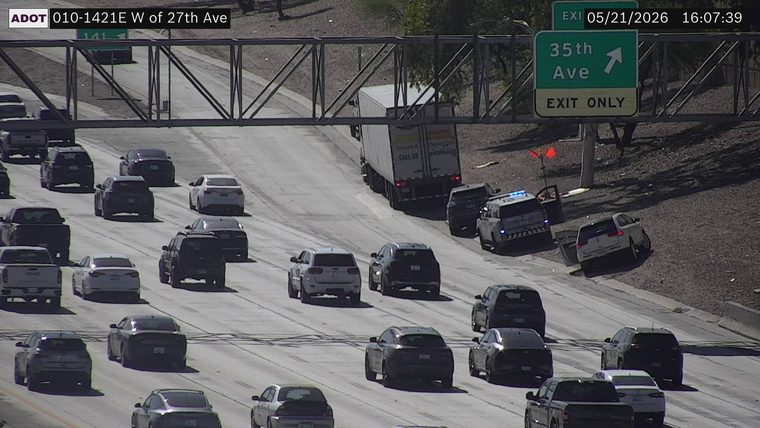 A white SUV has run off the highway onto the right shoulder embankment, with a police vehicle and other stopped cars responding at the scene.