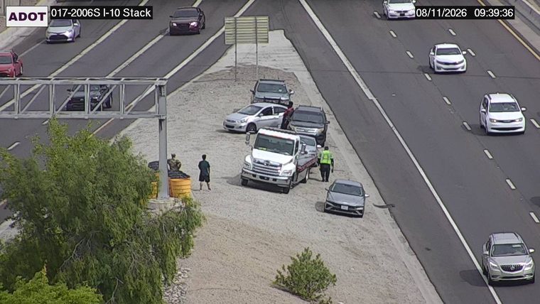 Tow truck assisting a silver sedan on the shoulder