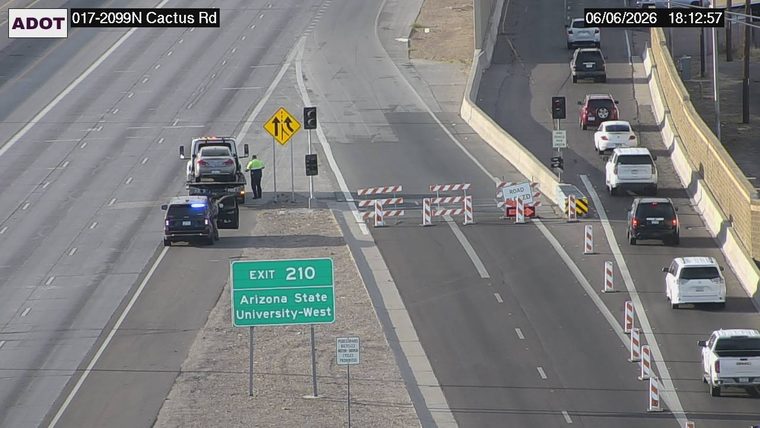 Tow truck and police car on the right shoulder with a person standing nearby