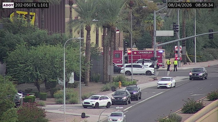 Fire truck with red flashing lights and two individuals in high-visibility vests near the intersection