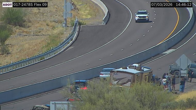 Several people standing near an RV and a pickup truck on the right shoulder