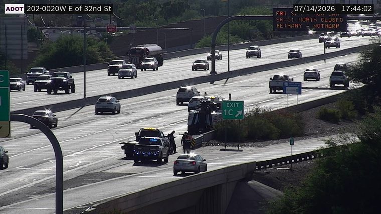 Police car and tow truck with people around a vehicle in the right lane