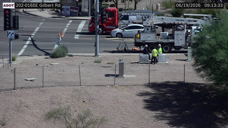 Two workers in high-visibility vests near a utility truck on the side of the road
