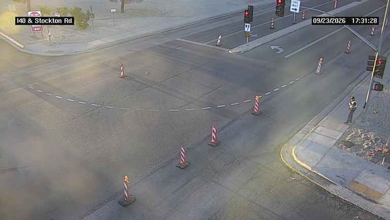 Construction cones and a person in a high-visibility vest on the sidewalk