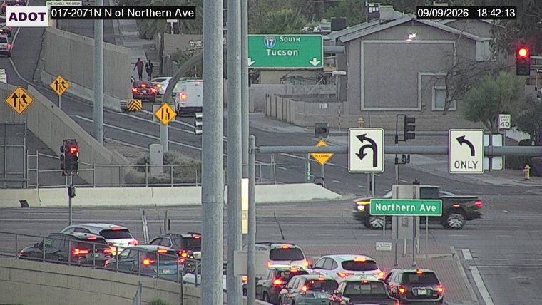 Two pedestrians on the roadway near a red car