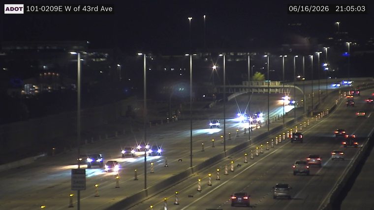 Multiple police cars with flashing blue and red lights in the left lanes