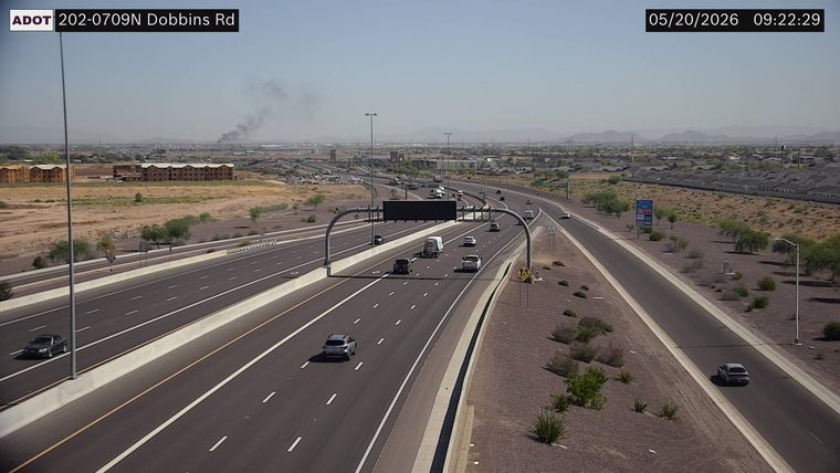 Dark smoke plume rising in the background to the left of the highway