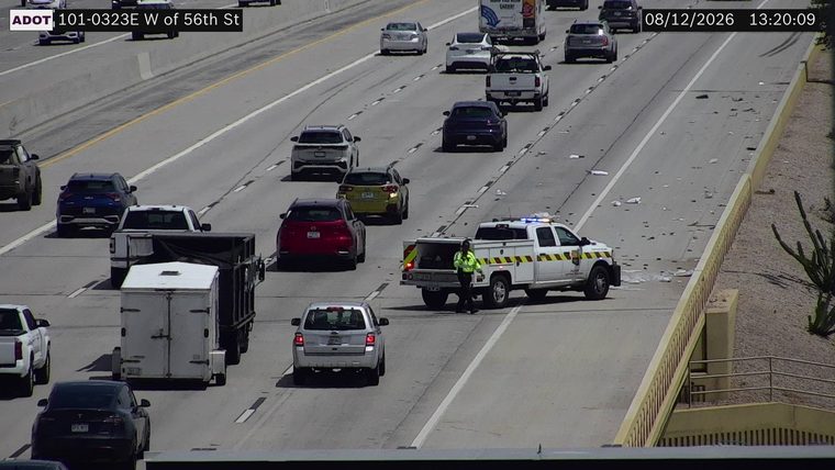 Service vehicle with blue and red lights on the right shoulder, with a person in a hi-vis vest standing nearby.