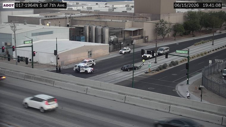 Two police cars and a black sedan in the intersection