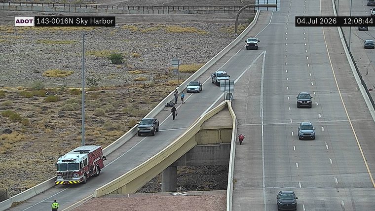 Fire truck and several people near a motorcycle on the left shoulder