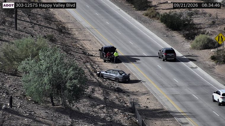 Damaged sedan off the roadway with a pickup truck assisting