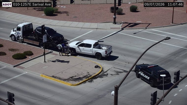 Two vehicles collided in the intersection, with one vehicle on a tow truck and another damaged pickup truck with a police car present.