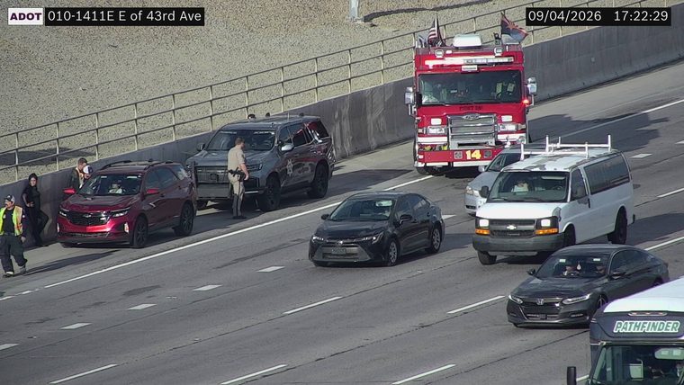 Fire truck and a police SUV on the right shoulder with people around a red SUV