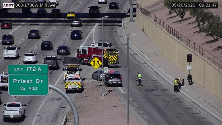 Emergency responders, including a fire truck, police vehicle with lights, and ADOT motorist assistant, are on the right shoulder and ramp area with personnel on foot.