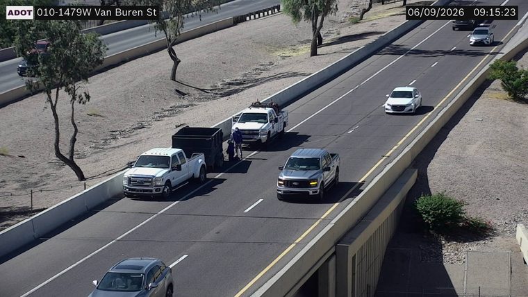 Two people standing next to a white pickup truck and a trailer in the right lane
