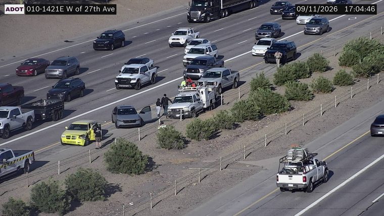 Yellow car with visible front-end damage and open driver door on the right shoulder