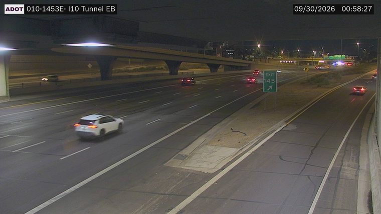 Multiple police cars with red and blue lights on the right shoulder