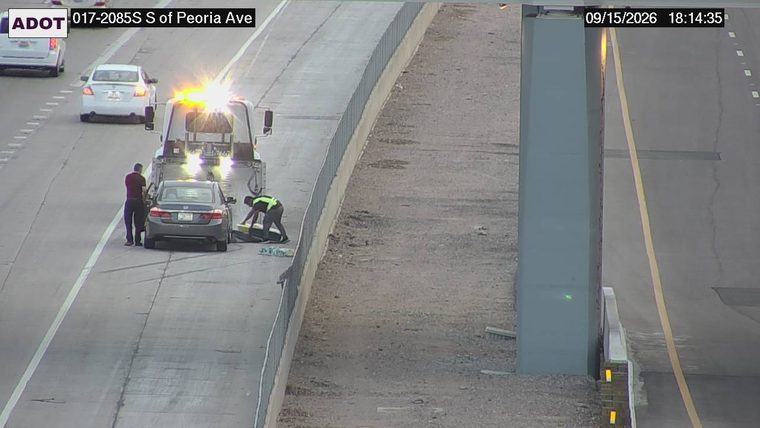Tow truck with flashing amber lights assisting a car on the right shoulder