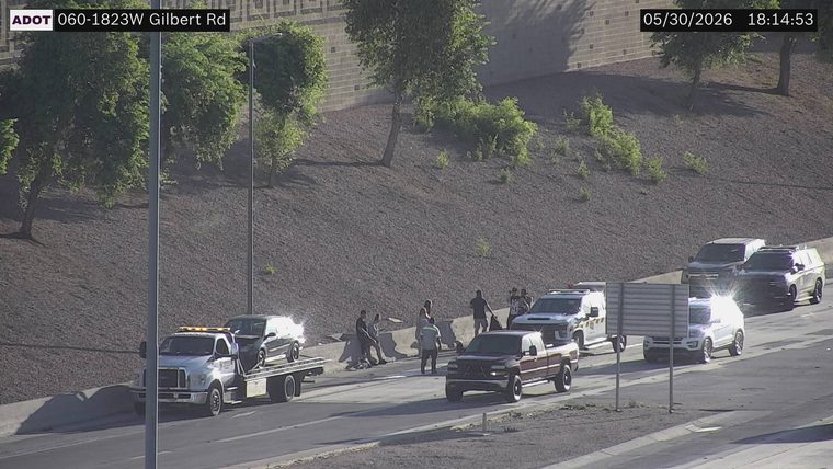 Tow truck with a car on its bed and several people gathered on the right shoulder