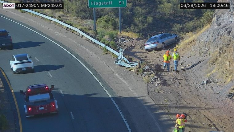 Silver sedan off the roadway, guardrail damaged, two workers on scene