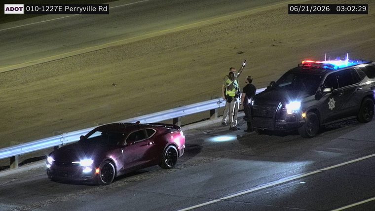 Police vehicle with red and blue lights on the shoulder next to a maroon car