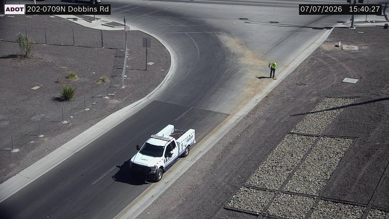 Worker with high-visibility vest and shovel on the right side of the roadway