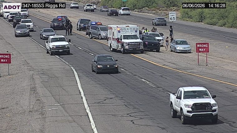 Ambulance and multiple police vehicles with people standing around in the right lane