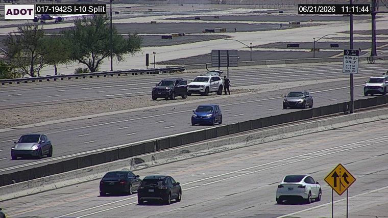 Person standing next to two SUVs on the right shoulder