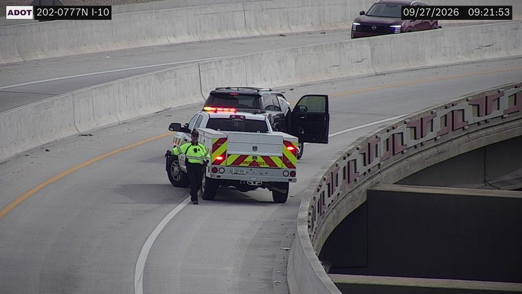 ADOT service truck with a person in hi-viz vest and an SUV with its door open on the right shoulder