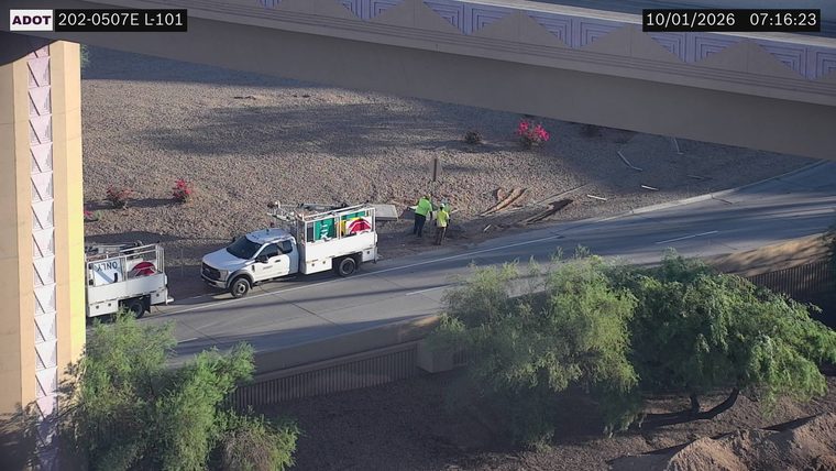 Two workers in high-visibility vests near a utility truck on the right shoulder