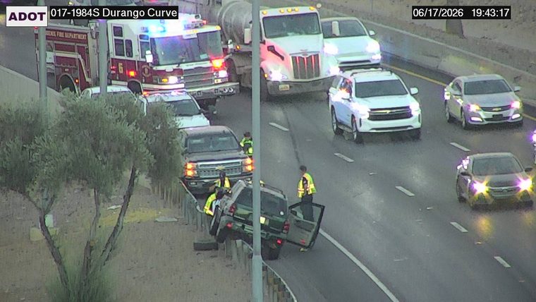Fire truck and police car with lights on near a damaged vehicle on the median barrier