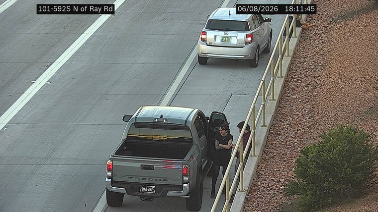 Pickup truck with open door and two people standing beside it on the shoulder