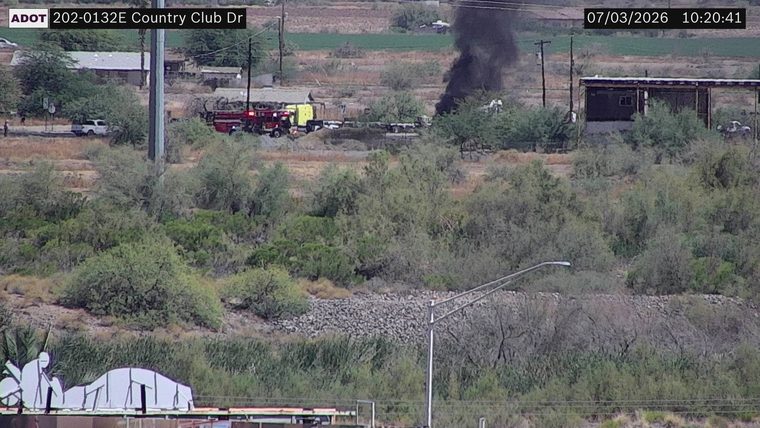 Fire and smoke plume visible near a fire truck and yellow vehicle