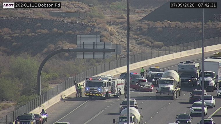 Fire truck and police car with lights on near a damaged red car in the left lanes