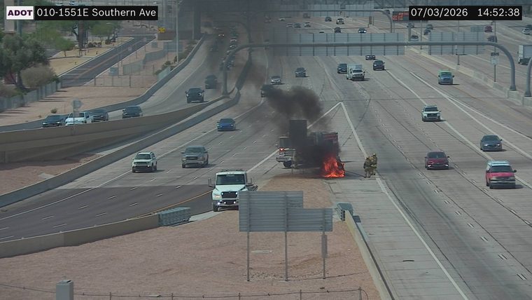 Truck on fire with two firefighters present in the right lane
