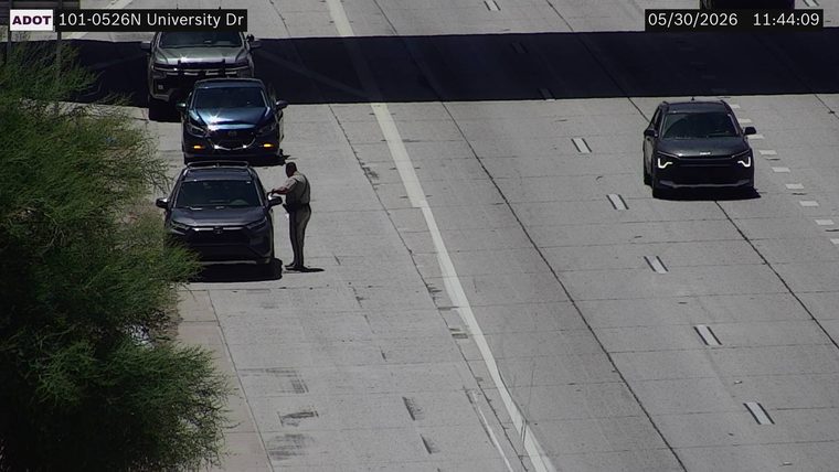 Officer standing next to a dark SUV on the right shoulder