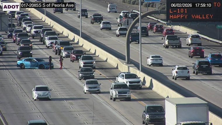Two people standing next to a blue car in the left lane