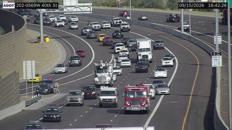 Two vehicles collided in the median, with one vehicle showing significant front-end damage and a police car with lights on next to it.