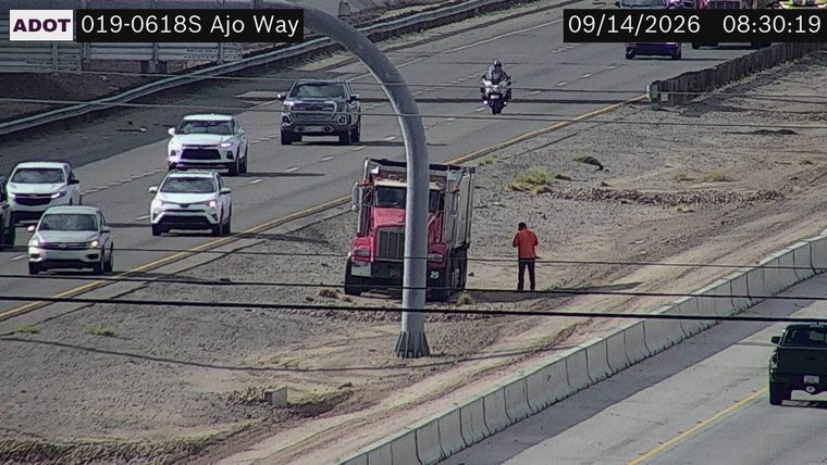 Person standing next to a dump truck off the travel lanes