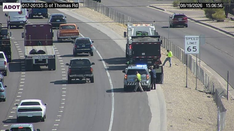 Police car with blue lights on the shoulder next to a dump truck