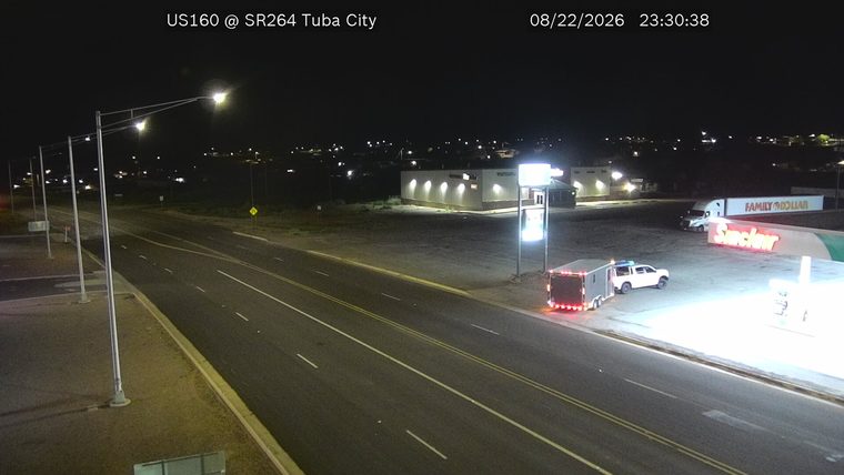 White pickup truck with a trailer and flashing blue and red lights on the shoulder