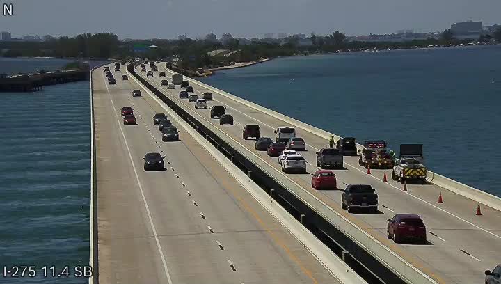 Emergency responders and vehicles are present on the right shoulder of the highway.