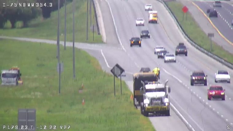 Oversize load truck and crew on the shoulder with traffic moving past.