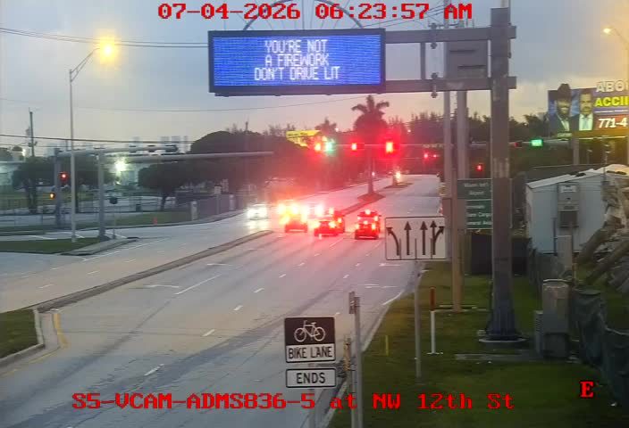 Three fire trucks with flashing red and blue lights in the travel lanes