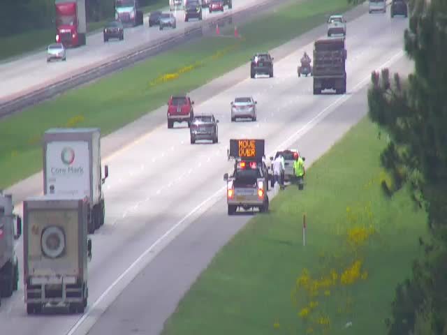 Traffic incident with "MOVE OVER" sign and responders on the shoulder.
