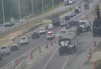 Police and construction vehicles are present on the roadway, indicating an incident.