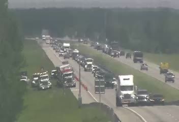 Emergency responders and traffic cones are present on the highway shoulder.