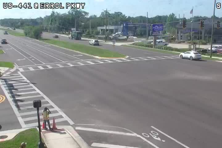 Person in reflective vest and cones at intersection, possibly directing traffic.