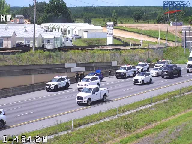 Multiple police vehicles and personnel on the highway shoulder.