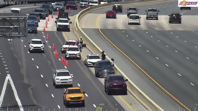 Police and EMS vehicles on scene with personnel and cones on the highway.